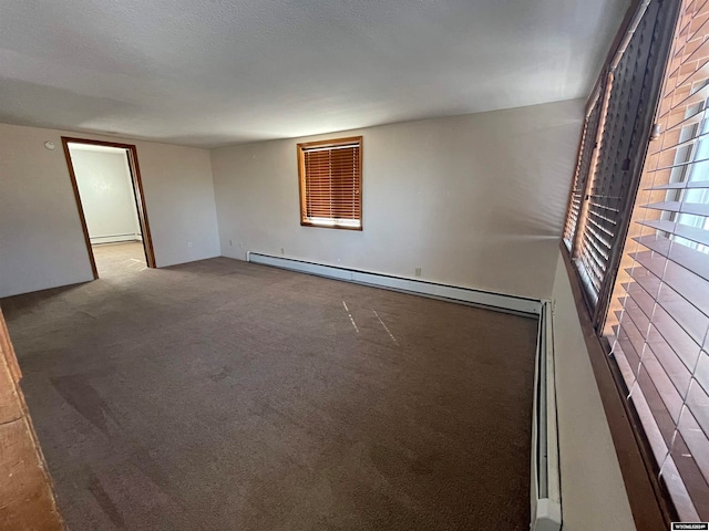 carpeted spare room featuring a baseboard heating unit and a wealth of natural light