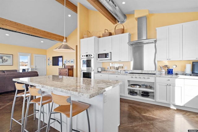 kitchen with pendant lighting, white microwave, stainless steel double oven, white cabinetry, and wall chimney exhaust hood