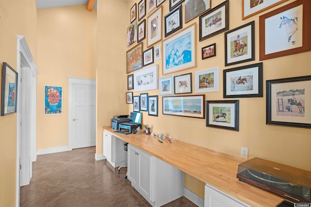 tiled home office with built in desk and a towering ceiling