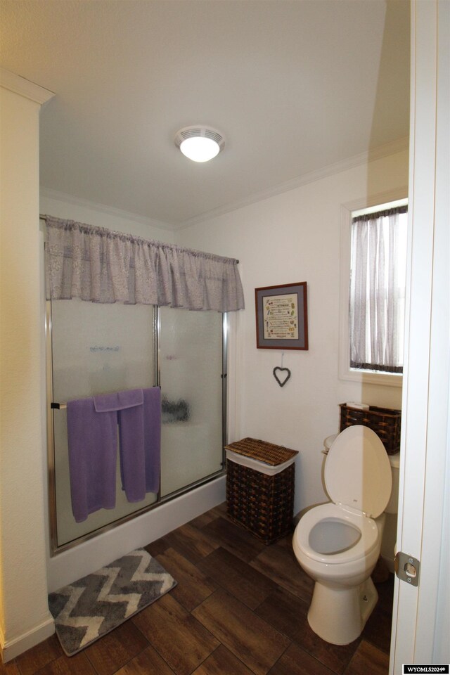 bathroom featuring ornamental molding, hardwood / wood-style floors, a shower with shower door, and toilet