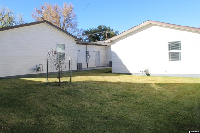 view of side of property featuring cooling unit and a lawn