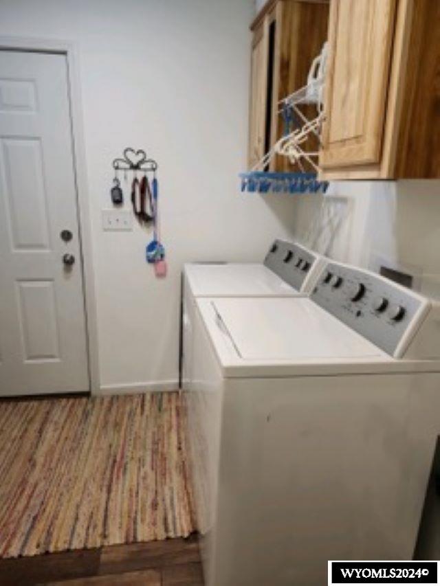 laundry area with hardwood / wood-style floors, cabinets, and independent washer and dryer