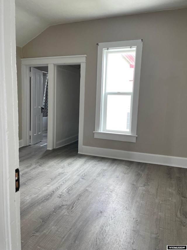 unfurnished room with lofted ceiling and light wood-type flooring