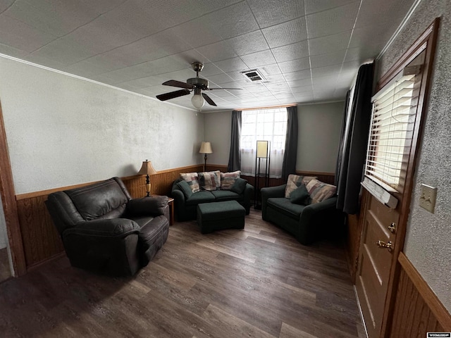 living room with ceiling fan, crown molding, and dark wood-type flooring