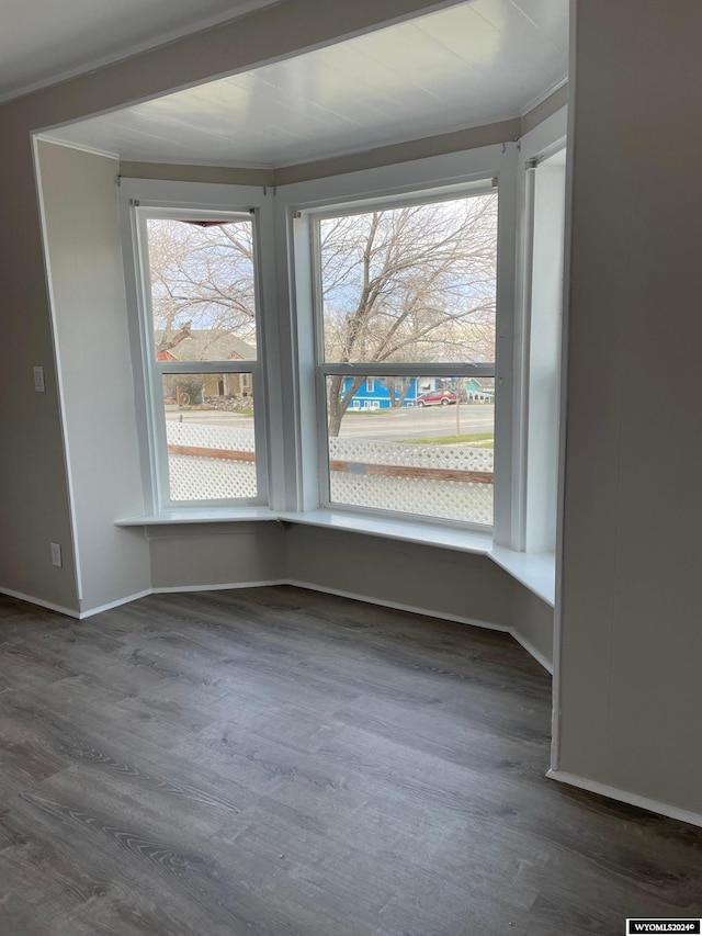 spare room featuring ornamental molding, dark wood-type flooring, and a wealth of natural light