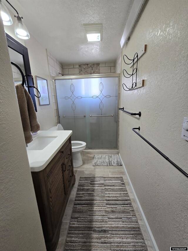 bathroom with walk in shower, toilet, tile flooring, a textured ceiling, and vanity