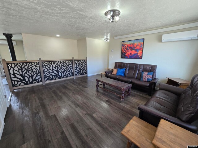 living room with dark hardwood / wood-style flooring, a wood stove, a wall unit AC, and a textured ceiling