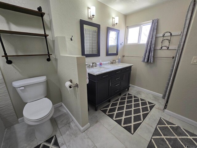 bathroom featuring toilet, tile floors, and dual bowl vanity