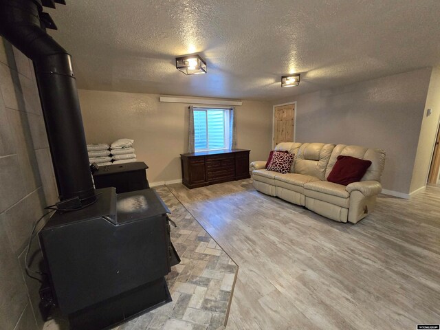 living room featuring a textured ceiling, a wood stove, and light wood-type flooring