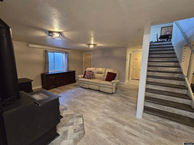 living room featuring a wood stove, a textured ceiling, and light hardwood / wood-style floors