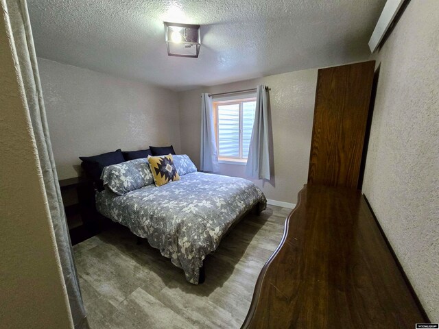 bedroom with a textured ceiling and hardwood / wood-style flooring