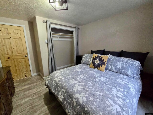 bedroom featuring a closet, dark hardwood / wood-style flooring, and a textured ceiling