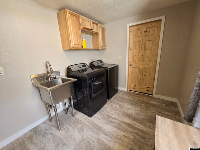 clothes washing area featuring light hardwood / wood-style flooring, cabinets, independent washer and dryer, and a textured ceiling