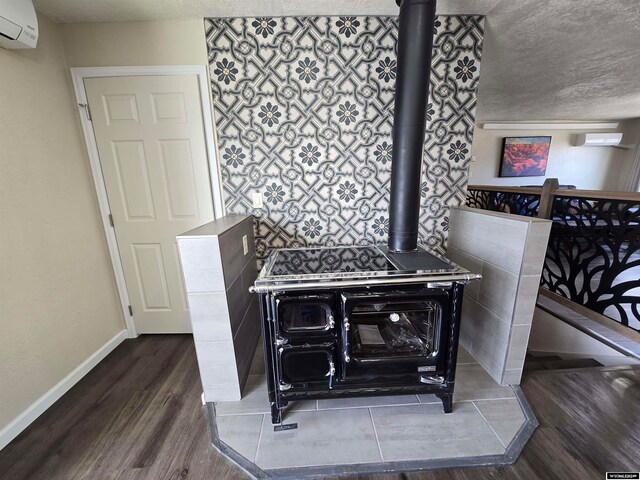 interior details featuring a wood stove, dark wood-type flooring, a wall mounted air conditioner, and a textured ceiling