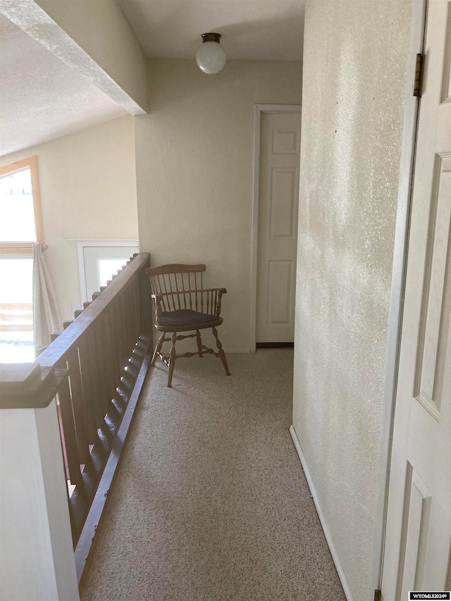 corridor featuring light carpet and a textured ceiling