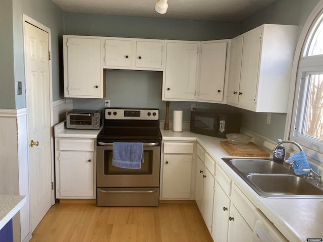 kitchen featuring dishwasher, white cabinets, sink, light wood-type flooring, and stainless steel electric stove