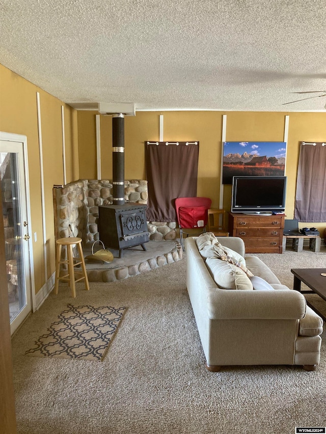 living room featuring a textured ceiling, a wood stove, and carpet