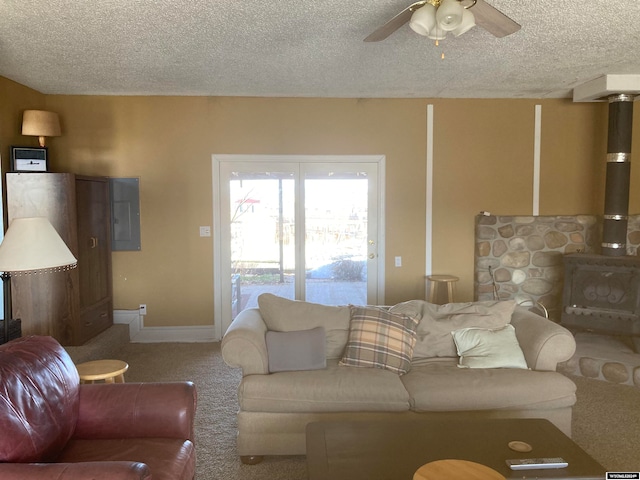 carpeted living room featuring ceiling fan, a wood stove, and a textured ceiling