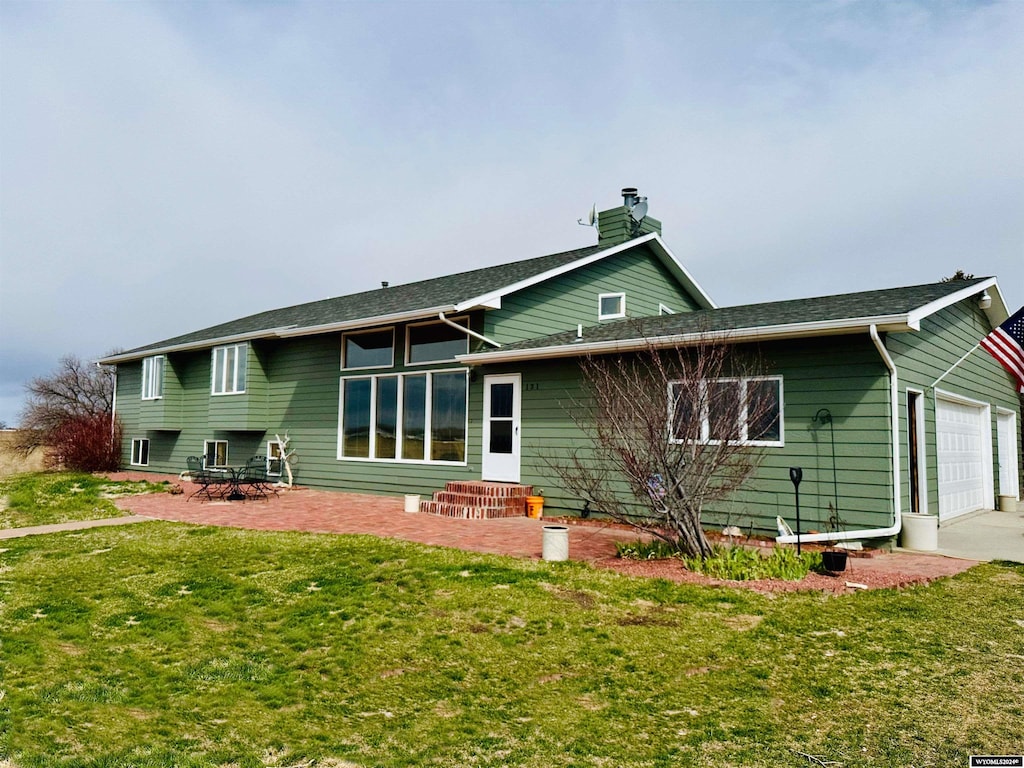 back of property featuring a garage and a yard