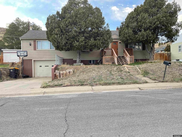 view of front of property with driveway, a garage, a shingled roof, a chimney, and fence