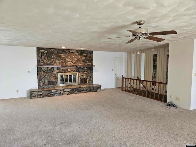 unfurnished living room with ceiling fan, carpet flooring, a fireplace, and a textured ceiling