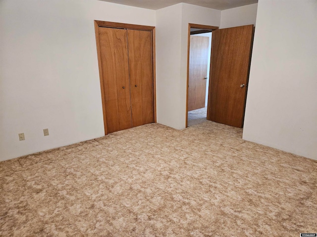 unfurnished bedroom with light carpet and a closet