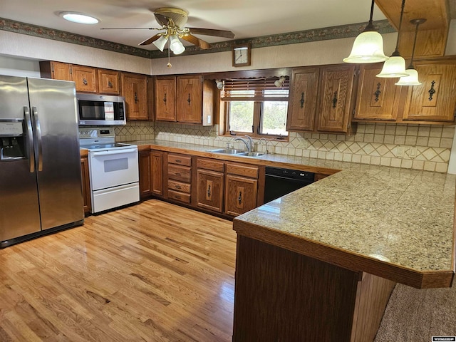 kitchen with kitchen peninsula, appliances with stainless steel finishes, light hardwood / wood-style flooring, tasteful backsplash, and pendant lighting