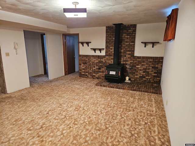 living room with a wood stove, dark carpet, and brick wall