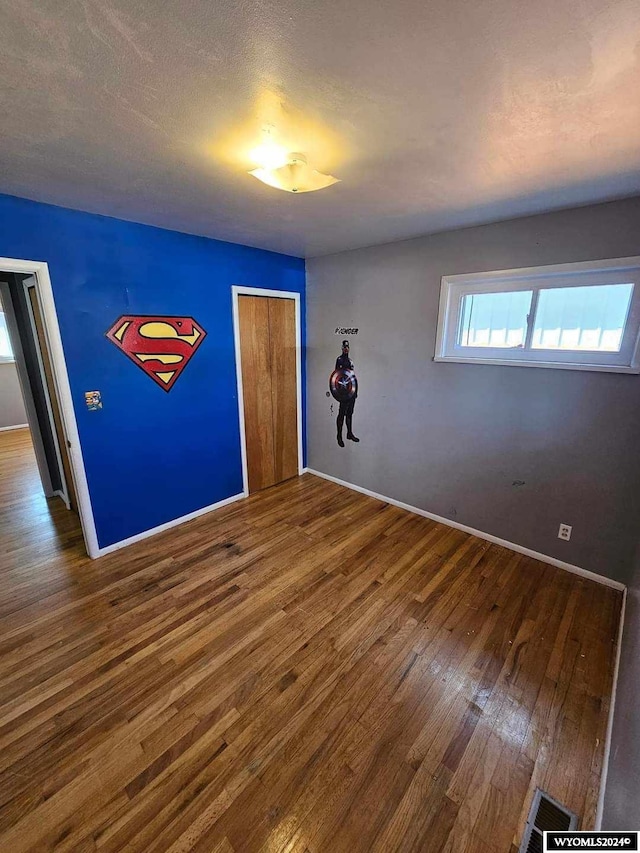 empty room with dark hardwood / wood-style flooring and a textured ceiling