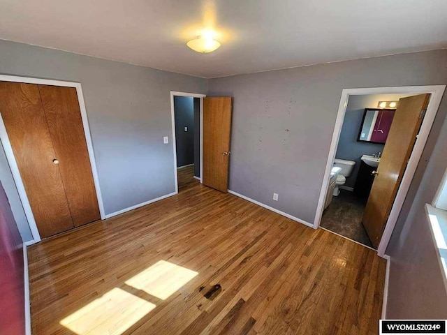 unfurnished bedroom with dark wood-type flooring, connected bathroom, and a closet