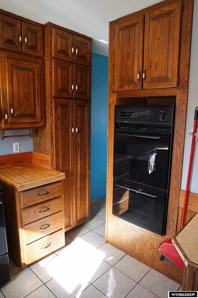 kitchen with black double oven and light tile flooring