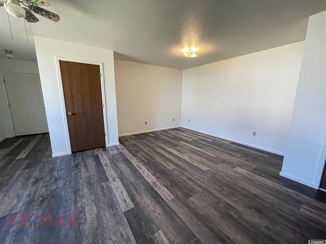 spare room featuring dark wood-type flooring, ceiling fan, and a textured ceiling