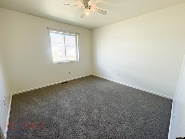 spare room featuring ceiling fan and dark carpet