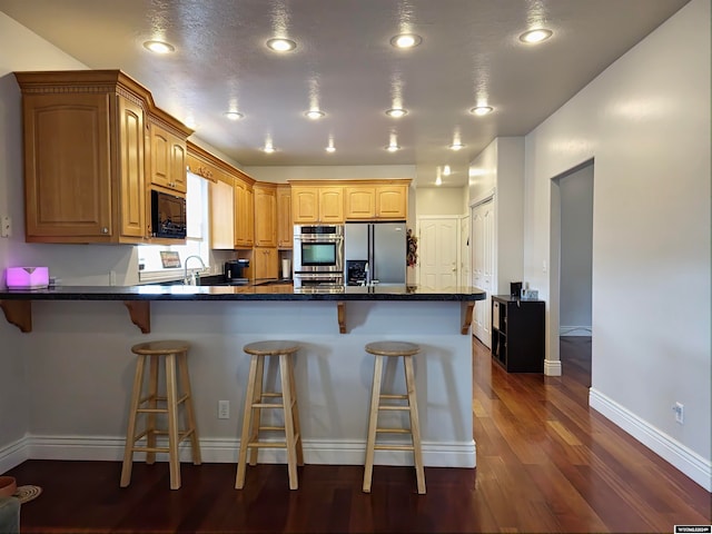 kitchen featuring stainless steel refrigerator with ice dispenser, dark hardwood / wood-style floors, kitchen peninsula, and a breakfast bar area