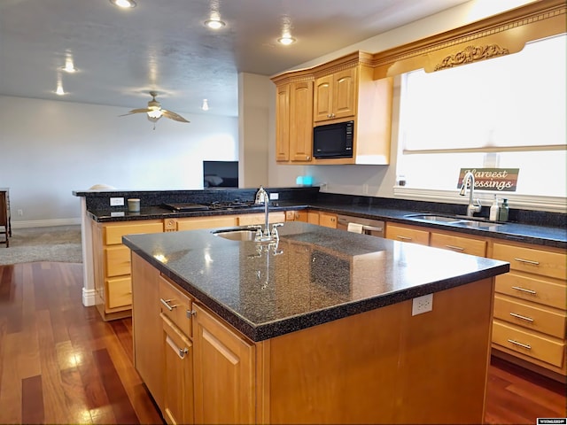 kitchen featuring dark wood-type flooring, sink, a center island with sink, and black microwave