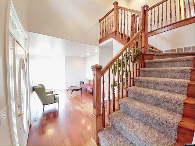 stairway featuring hardwood / wood-style floors and a high ceiling