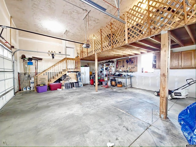 garage with a garage door opener and white refrigerator with ice dispenser