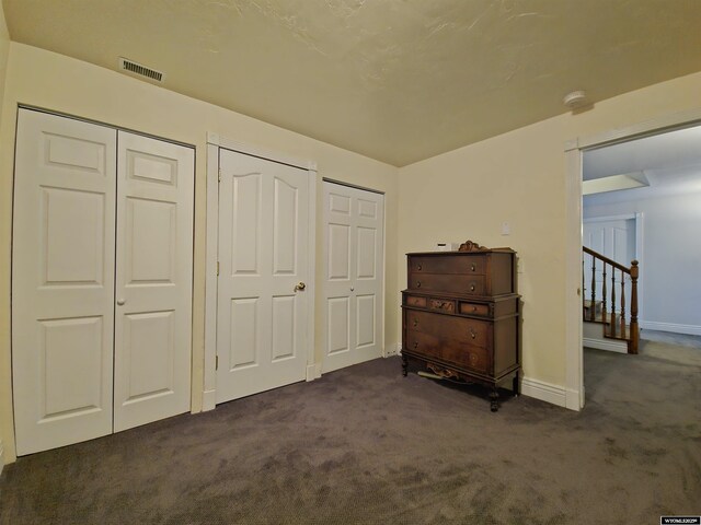 bedroom with multiple closets and dark carpet