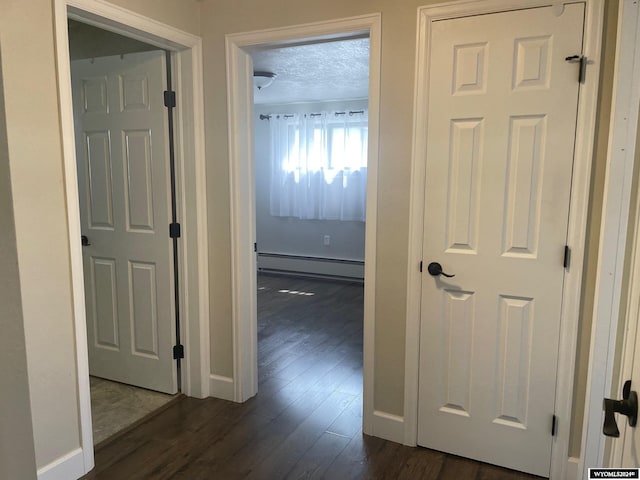 hall featuring a textured ceiling, dark hardwood / wood-style floors, and a baseboard radiator