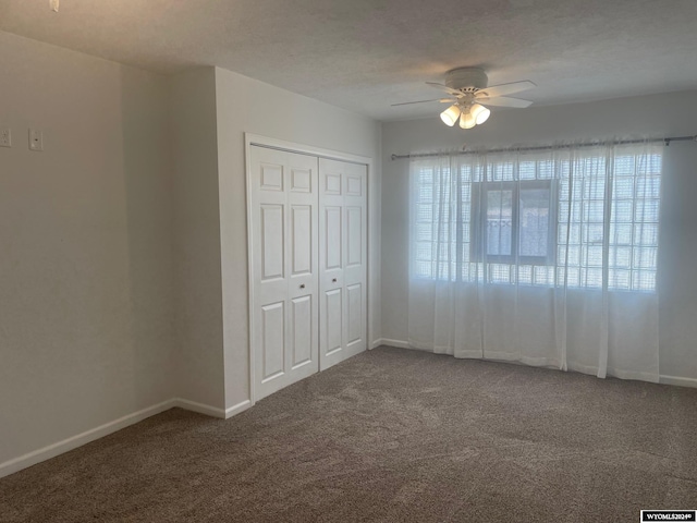 unfurnished bedroom featuring a closet, ceiling fan, and dark colored carpet