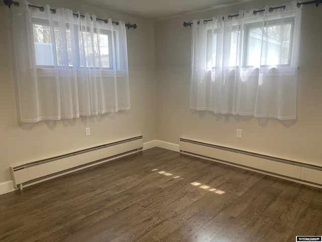 spare room featuring a baseboard radiator, a wealth of natural light, and dark wood-type flooring