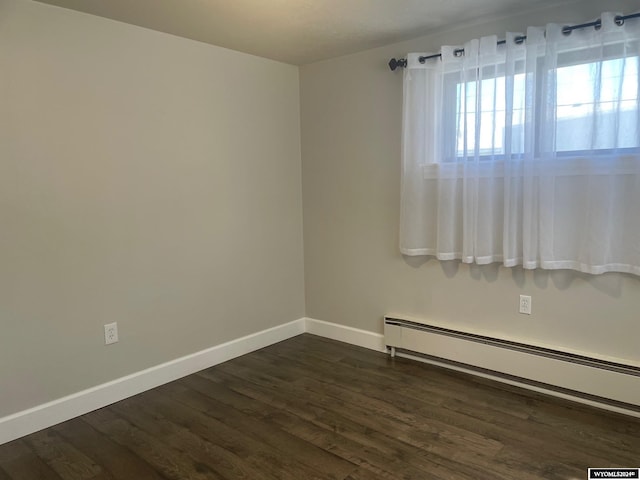 empty room with dark hardwood / wood-style floors and baseboard heating