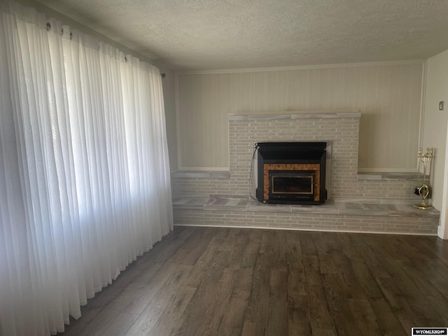 unfurnished living room featuring a wealth of natural light, dark hardwood / wood-style floors, a textured ceiling, and a fireplace