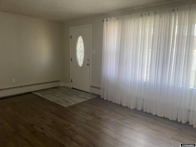 entryway with a baseboard radiator, a wealth of natural light, hardwood / wood-style flooring, and a textured ceiling