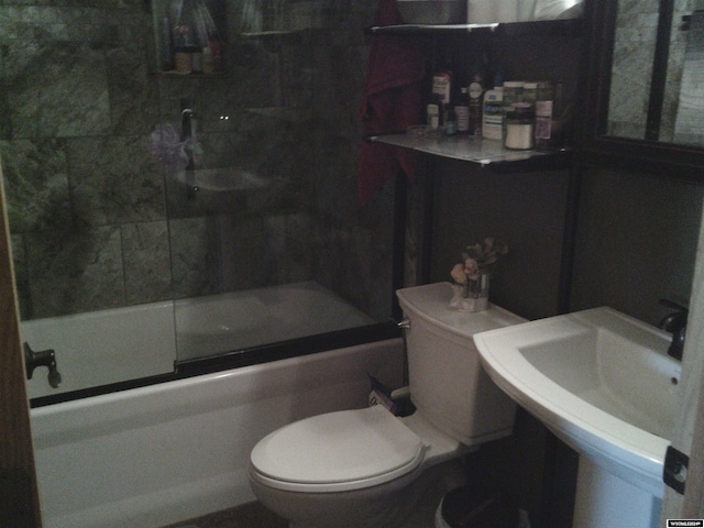 full bathroom featuring toilet, combined bath / shower with glass door, and sink