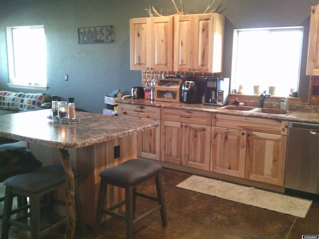 kitchen featuring a kitchen bar, sink, dishwasher, and backsplash