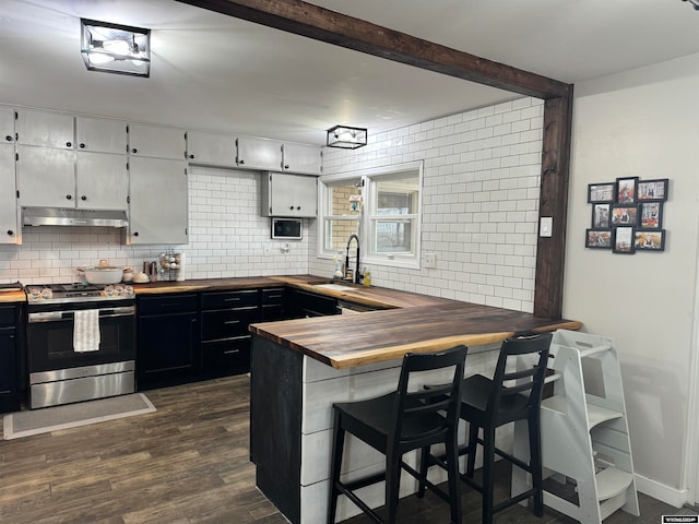 kitchen featuring stainless steel range oven, kitchen peninsula, dark wood-type flooring, sink, and a breakfast bar