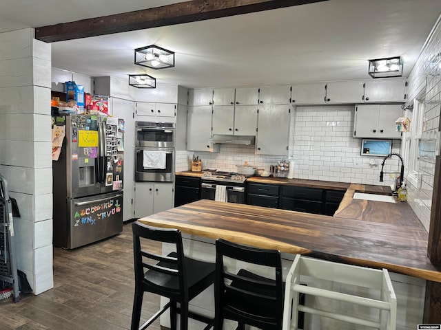 kitchen featuring sink, tasteful backsplash, dark hardwood / wood-style flooring, wood counters, and stainless steel appliances