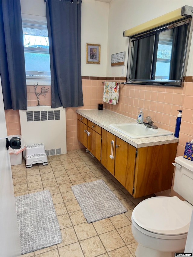 bathroom featuring vanity, tile walls, backsplash, toilet, and radiator heating unit