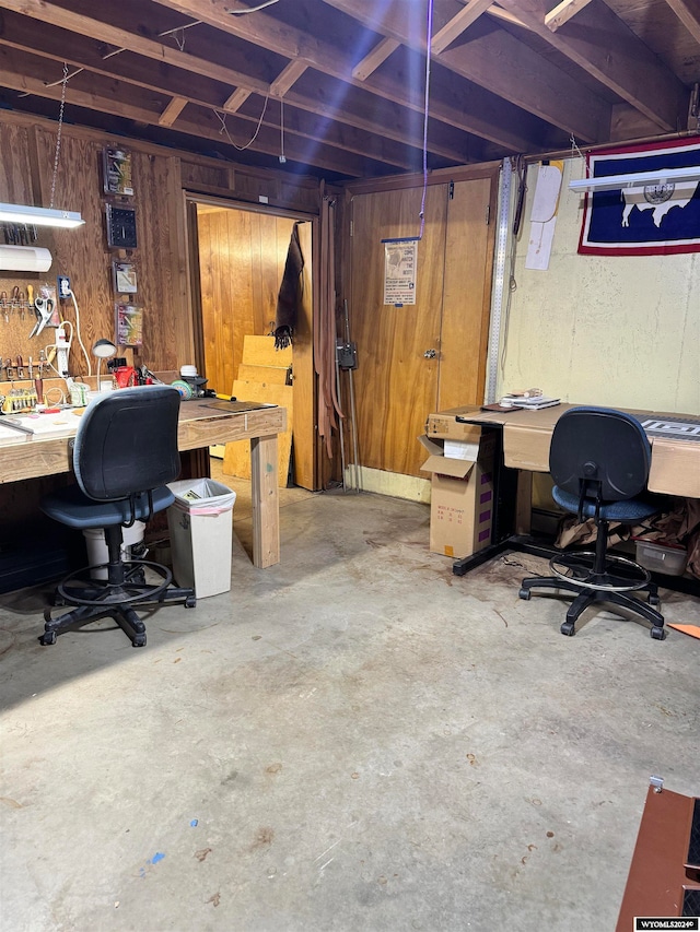 office featuring concrete flooring, a workshop area, and wooden walls